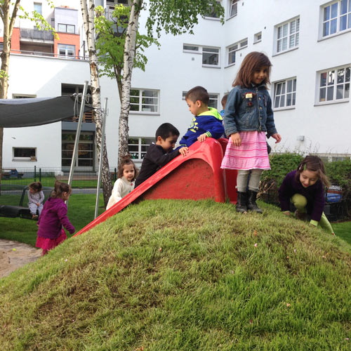 Kita-Kinder an der Rutsche im Garten